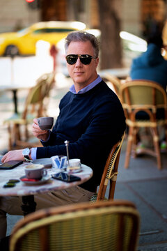Mature man sitting at a table in a cozy European outdoor cafe