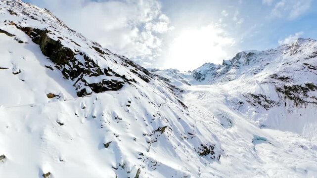 Drone view flying over snow-covered mountain slopes toward Morteratsch Glacier in Graub&uuml;nden, Switzerland. Aerial forward