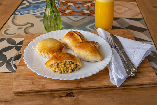 Brazilian empadas on white plate with orange juice