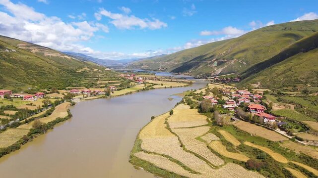 Aerial view of river valley farmland and villages between green mountains