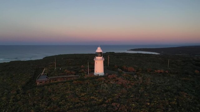 White lighthouse on coastal headland at sunset