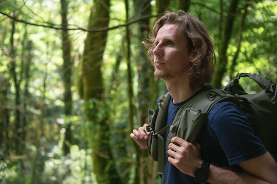 Young man traveler with backpack hiking in the forest. Close up portrait.  Travel and adventure concept