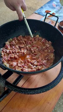 Chef flambeing pork ears in a pan