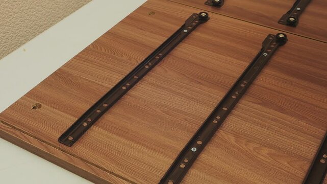 A furniture assembler screws drawer strips into place using a screwdriver