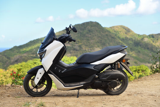 White modern maxi scooter parked against a mountain landscape.
