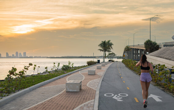 Woman Jogging on Waterfront Bike Path at Sunset in Miami