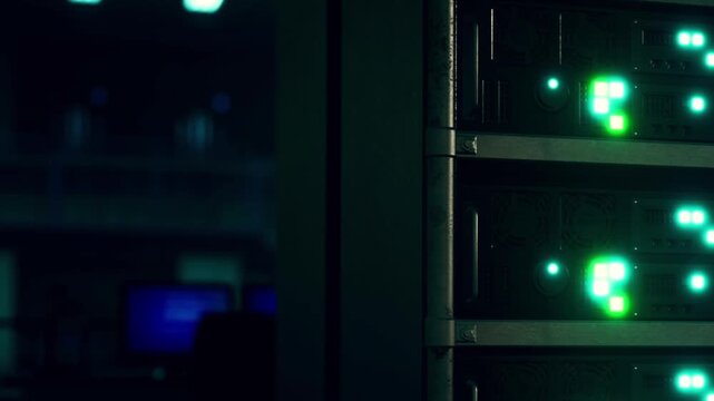 Several server units with green lights are visible in a dark data center. The setup shows a busy environment with electronic devices and equipment.