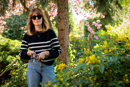 Mid-aged woman and removing old stems and leaves in a back yard