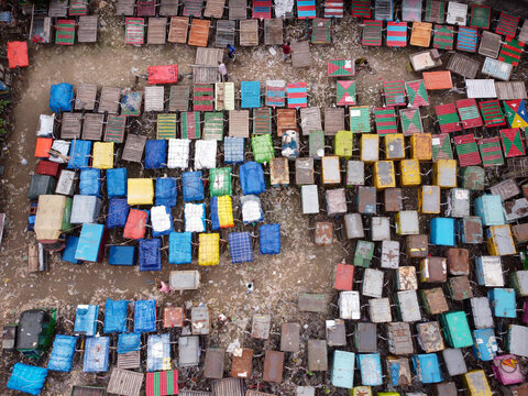 Aerial view of the colorful van stand featuring rows of parked rickshaws and transport vehicles with vibrant tarpaulin covers in Narayanganj, Dhaka, Bangladesh.