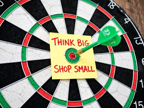 dartboard with a post-it note that reads think big shop small