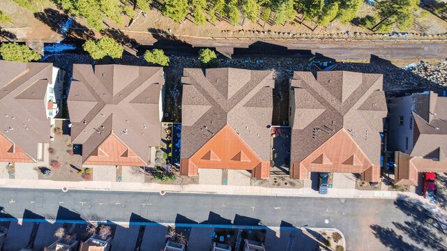 Aerial view of suburban townhouse row with uniform roofs and street