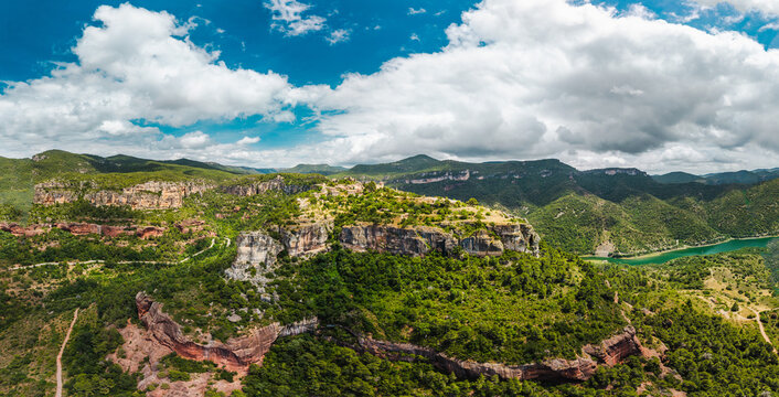 Panoramic aerial view of Siurana perched on towering cliffs above a winding reservoir in Catalonia, Spain.