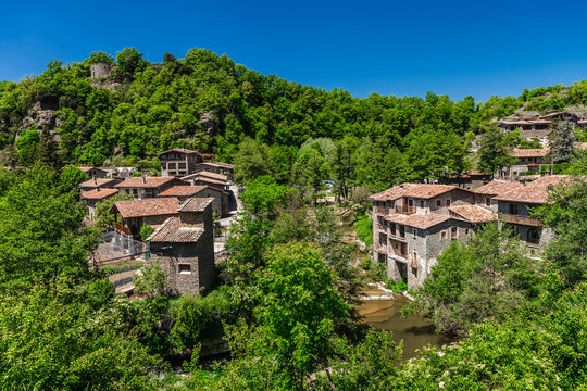 Panoramic landscape of Rupit village in Catalonia, Spain, featuring medieval stone houses, forested hills
