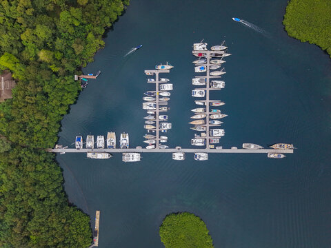 Aerial view of a marina with numerous yachts and sailboats docked at piers surrounded by lush green mangroves on Bastimentos Island, Bocas del Toro Provin, Panama.