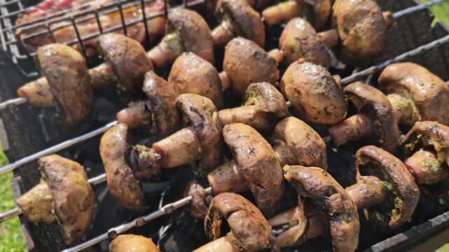 Grilling mushrooms and meat on a barbecue during a sunny day in a backyard gathering
