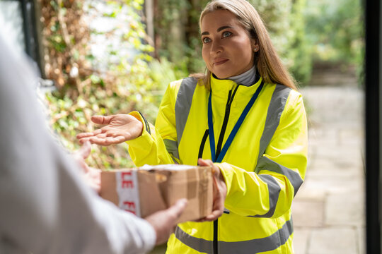 Delivery person holding a damaged package and offering an apology with an apologetic gesture. The torn parcel was damaged during delivery, illustrating poor delivery service, shipping problems