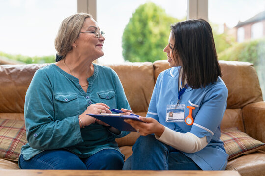 Caregiver talks with patient during a home visit in a living room setting