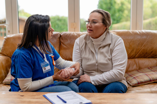Woman speaks with a caregiver in a cozy living room in the afternoon