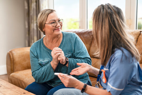 Senior woman talks with caregiver in a cozy living room during a home visit