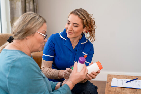 Nurse discussing medication with patient in a home setting during a daytime visit