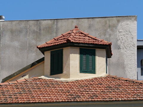 Traditional Mediterranean dormer window with green shutters and clay tiles