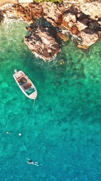 Vertical top down drone view of small boat floating in turquoise Adriatic sea Brela Croatia