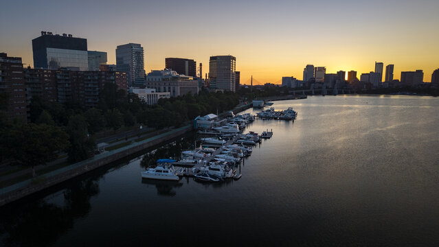 Aerial view of the Charles River Esplanade marina with docked boats and the Boston skyline illuminated by the warm glow of sunset in Boston, Massachusetts, United States.