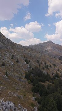 Vertical Drone Aerial View Flying Over Rocky Mountain Slope and Forest towards Peak under Blue Sky on Visocica