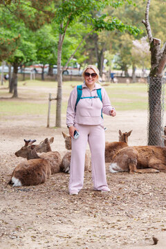 Tourist woman does a cheesy pose in front of wild deer in Nara Japan