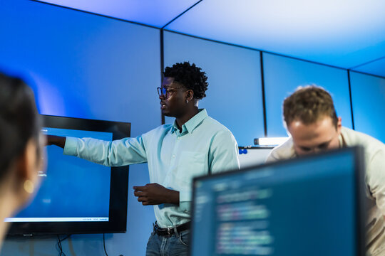 African male developer leads team discussion on workflow development and process optimization, collaborating with colleagues on AI-assisted strategy and team productivity enhancement.