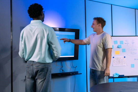 Diverse male developers collaborate on system architecture and workflow troubleshooting, demonstrating technical problem-solving and integrated solution design discussion.