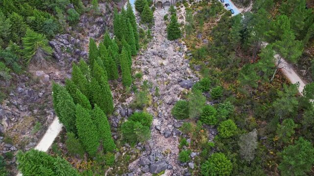 Horizontal aerial drone shot of Cascata do Arado waterfall surrounded by lush green rock formations and clear water pools in Peneda-Geres National Park, Portugal.