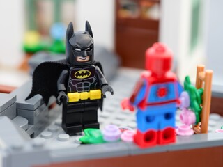 Naklejka premium Tambov, Russian Federation - August 23, 2026 A Lego Batman minifigure facing Spider-Man on a brick-built rooftop terrace.