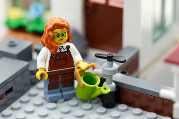 Naklejka premium Tambov, Russian Federation - August 22, 2026 A Lego woman gardener minifigure with a green watering can next to a water tap.