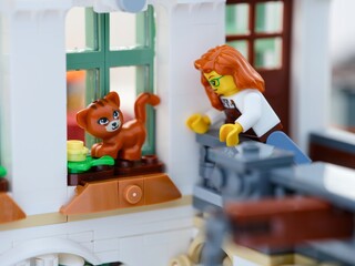 Naklejka premium Tambov, Russian Federation - August 22, 2026 A close-up shot of a Lego woman minifigure reaching out to rescue a ginger cat from a window sill.