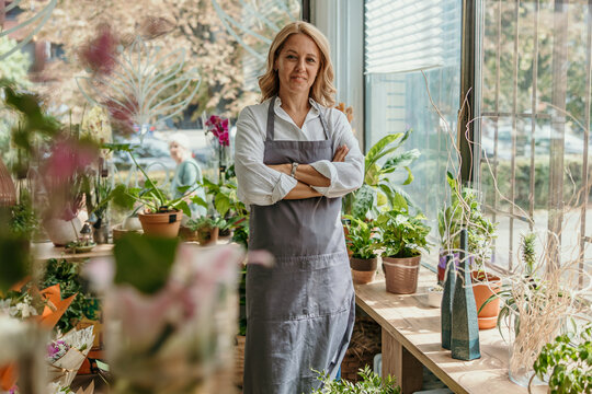 Smiling woman owner standing in her flower shop