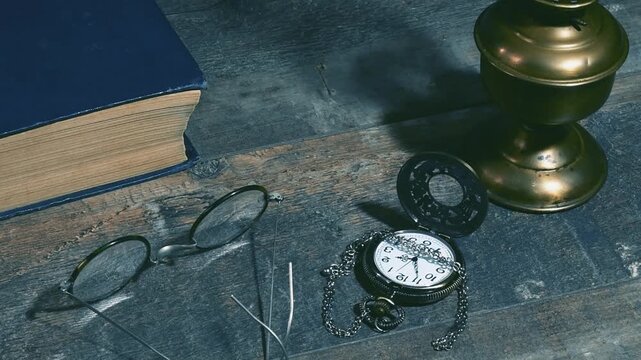 Vintage desk from the past setup with book, lamp, pocket watch, and glasses on the table
