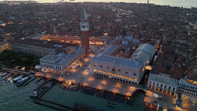 Venice, Italy. Aerial 4K panoramic night drone view of the city in dusk. Ancient Venice city skyline with channels, Palazzo Ducale, St Mark's square and other iconic buildings. Europe from above.