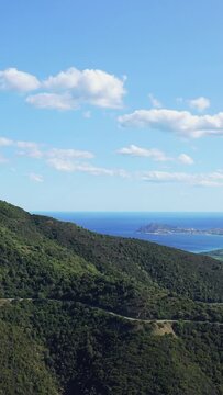 Vertical 9:16 aerial video showing lush green mountains descending towards the Mediterranean Sea between Baunei and Dorgali in Sardinia, Italy.