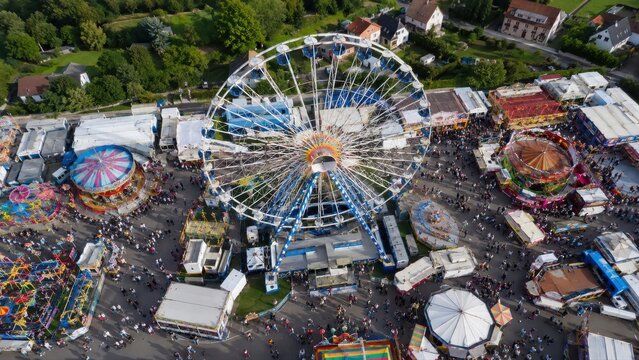 Riesenrad auf deutschem Volksfest aus der Luft &ndash; beeindruckender Drone Shot mit Fahrgesch&auml;ften, Buden und vielen Besuchern auf einem belebten Rummelplatz.