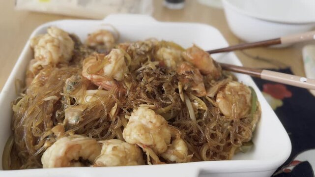 A flavorful homemade dish of translucent glass rice noodles served with juicy prawns and fresh vegetables. The delicate noodles absorb the savory sauce