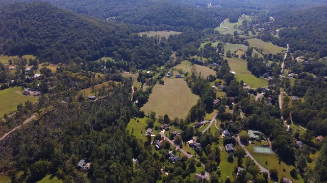  Drone advances over rural countryside toward layered hills and distant agricultural clearings in Blue Ridge mountain 

