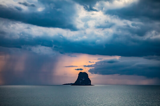 Storm clouds above a limestone island in a calm tropical sea. The Gulf of Siam.