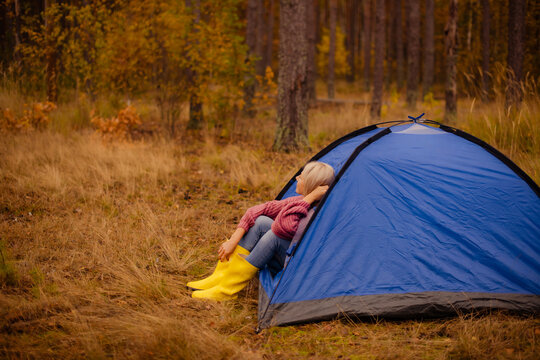 middle aged female hiker relaxing inside blue tent during fall camping trip