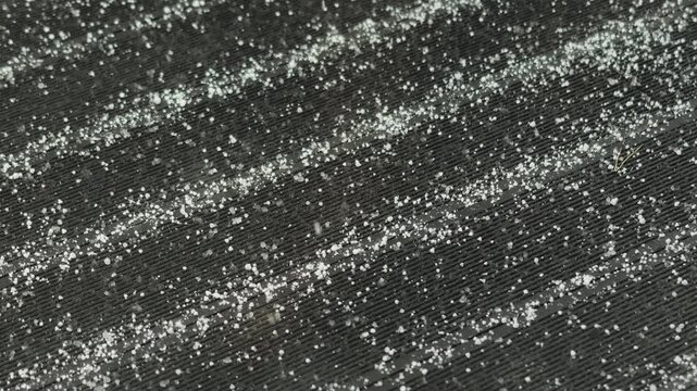 Fine snow falling across a dark roof surface, capturing a quiet cold winter atmosphere outdoors.