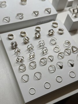 Display of elegant silver rings on a white background, showcasing various geometric designs