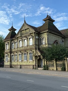 Wooden Victorian house with ornate details against clear blue sky, suitable for architectural background