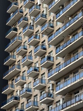 Urban high-rise building facade with numerous balconies, showcasing modern city architecture.