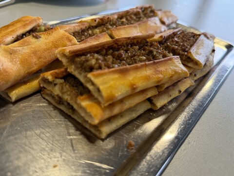 Turkish pide neatly arranged on metal tray, highlighting traditional flatbread dish background