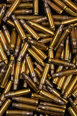 Pile of empty brass rifle bullet casings filling the frame entirely. © solidmaks